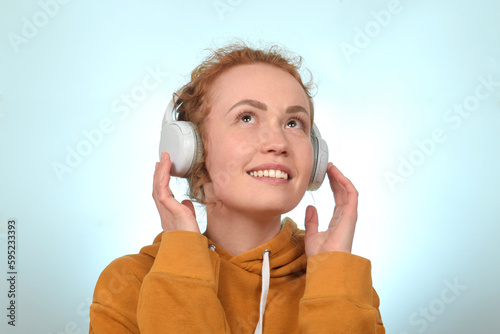 cute redhead curly woman enjoying music in headphones