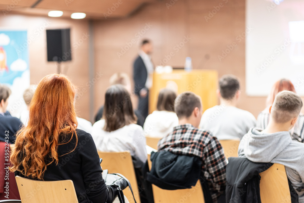 Speaker giving a talk in conference hall at business event. Rear view of unrecognizable people in audience at the conference hall. Business and entrepreneurship concept