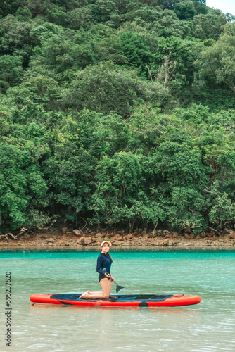 A single woman rowing in the middle of the sea enjoying the blue ocean view at the beach. Pictures of travel and relaxation at the sea of ​​Thailand.