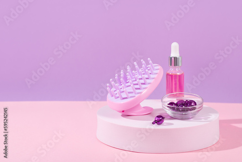 Scalp massage and cleansing shampoo brush with hair vitamins and serum on podium, copy space © Maria Shchipakina