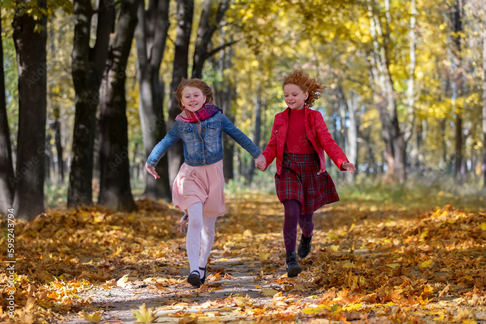 Happy children play in the autumn park on a warm sunny autumn day.