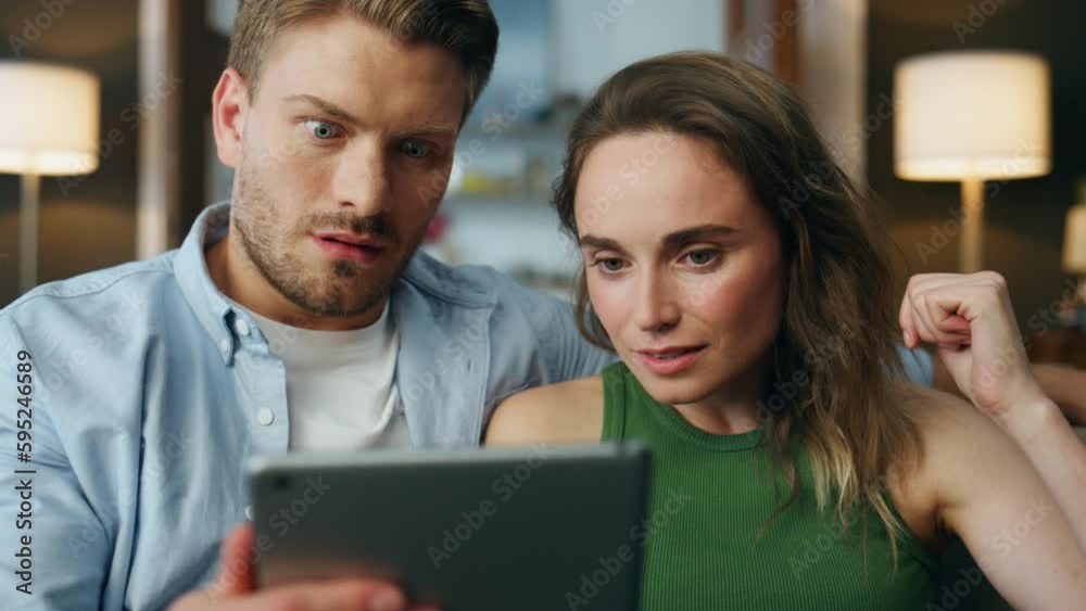 Surprised pair staring tablet home zoom on. Shocked spouses faces received bills Surprised pair staring tablet home zoom on. Shocked spouses faces received bills
