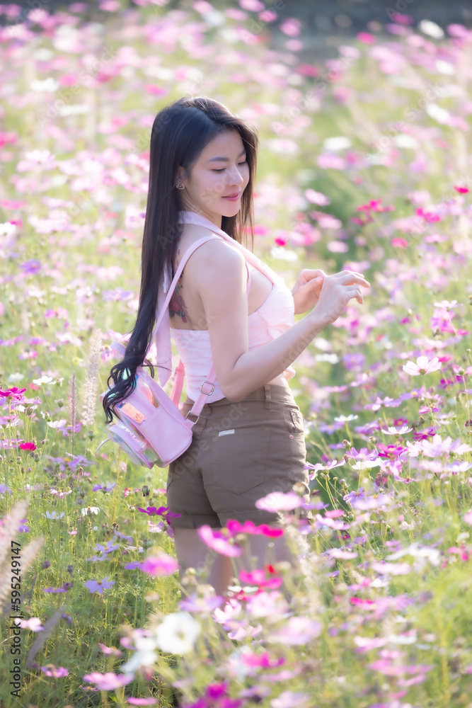 Beautiful woman happy traveler walking in the flowers garden. Young woman smile and relaxing with happy around outdoor garden. Woman's hand touching and enjoying beauty cosmos flowers.Travel concept. Beautiful woman happy traveler walking in the flowers garden. Young woman smile and relaxing with happy around outdoor garden. Woman's hand touching and enjoying beauty cosmos flowers.Travel concept.