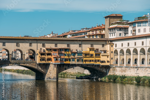 View of a stunning yellow colored stone medieval stone segmental arch bridge with closed lintels over the Arno river in Florence, Italy with tourists on a sunny summer day. Copyspace