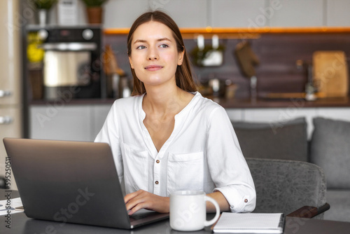 Portrait of dreamy Caucasian businesswoman sitting at desk in home office and thinking while working on laptop