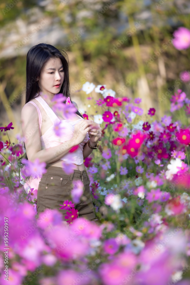 Beautiful woman happy traveler walking in the flowers garden. Young woman smile and relaxing with happy around outdoor garden. Woman's hand touching and enjoying beauty cosmos flowers.Travel concept. Beautiful woman happy traveler walking in the flowers garden. Young woman smile and relaxing with happy around outdoor garden. Woman's hand touching and enjoying beauty cosmos flowers.Travel concept.