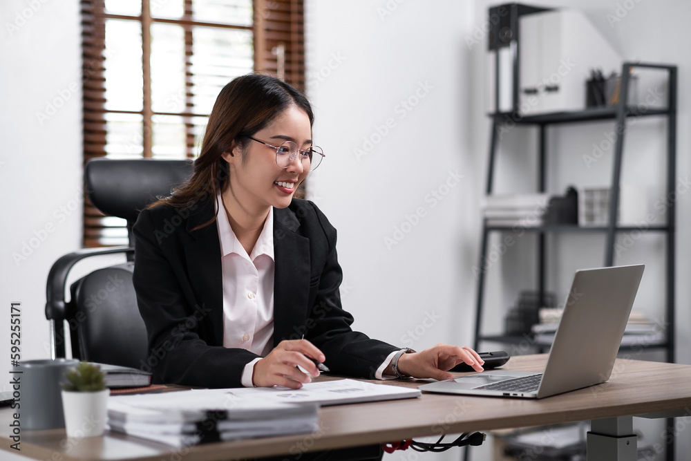 Young confident businesswoman sitting at the office table working on laptop computerr Young confident businesswoman sitting at the office table working on laptop computerr
