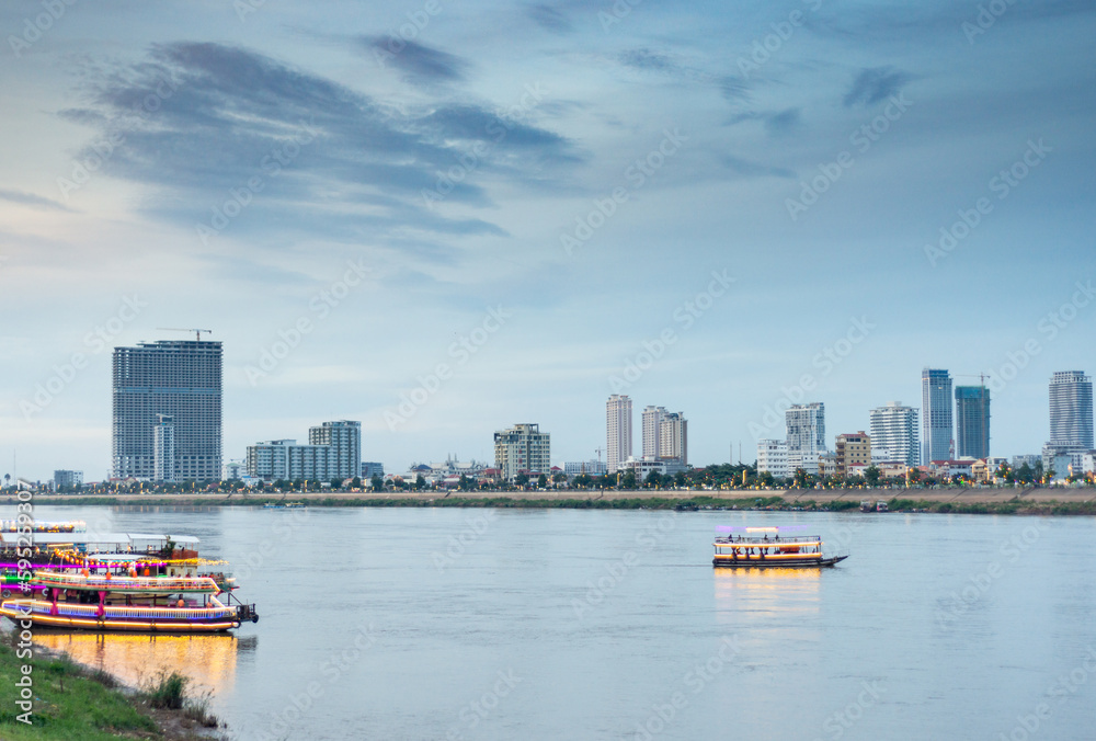 Naklejka premium River cruise boat drifting towards the Mekong,illuminated after sunset,Phnom Penh,Cambodia.