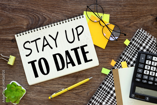 Stay Up To Date. text. Notepad, white sticker and pensil on the desk.
