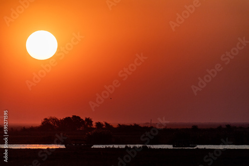 Telephoto shot of the setting sun over the chobe river on a bright winter afternoon in Botswana.