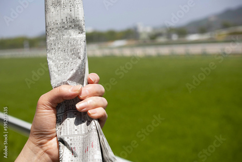 競馬新聞を握りしめる
