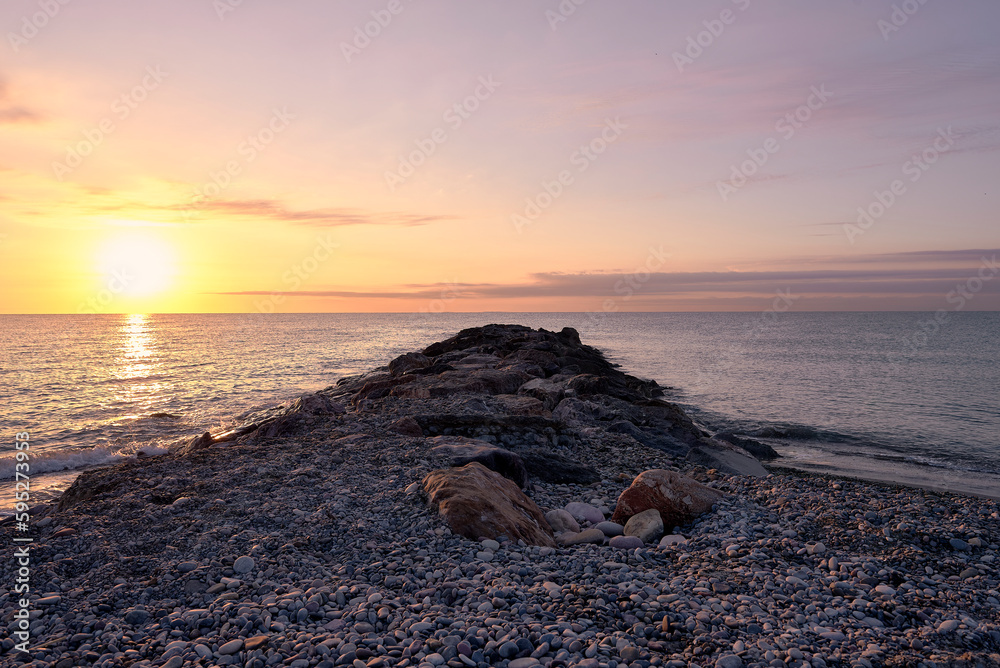 Obraz premium Breakwater on the rocky beach at sunrise
