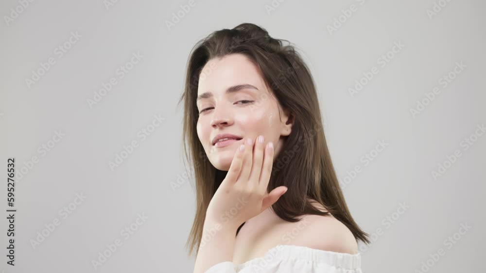 Funny happy attractive woman applying skin care cream on her face, looking at cameras and smiling, healthy young lady applying moisturizing face lifting cream, healthy skin care concept Funny happy attractive woman applying skin care cream on her face, looking at cameras and smiling, healthy young lady applying moisturizing face lifting cream, healthy skin care concept