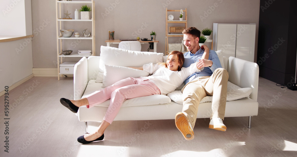 Couple Jumping On Sofa At Home