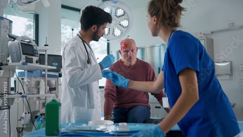 Young doctor and nurse treating injury of senior man. photo