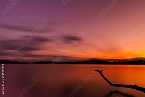 Beautiful landscape scene featuring an orange sunset in the distance over a tranquil lake