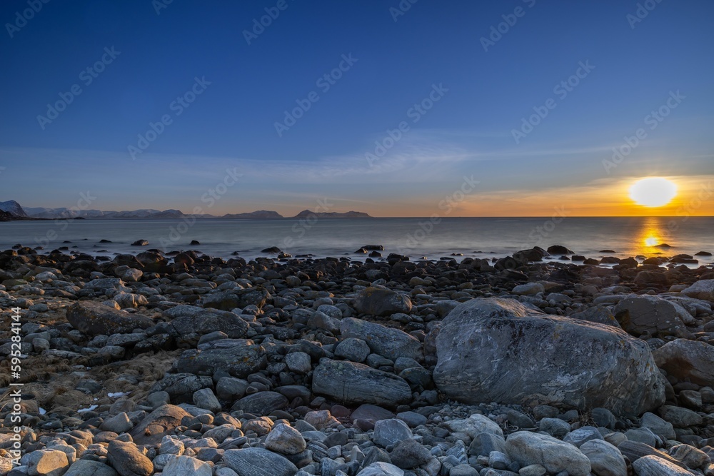 Stunning sunset silhouettes a coastal landscape of rocky cliffs jutting out against the horizon