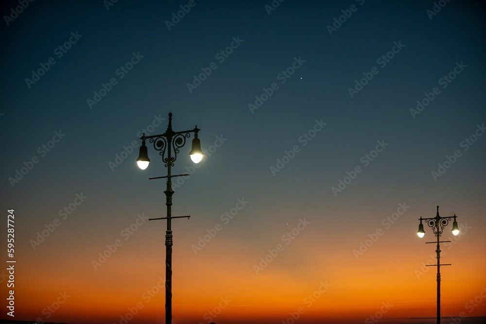 Beautiful shot of a bright orange blue sunset sky over lamp post silhouettes on Brighton Beach Beautiful shot of a bright orange blue sunset sky over lamp post silhouettes on Brighton Beach