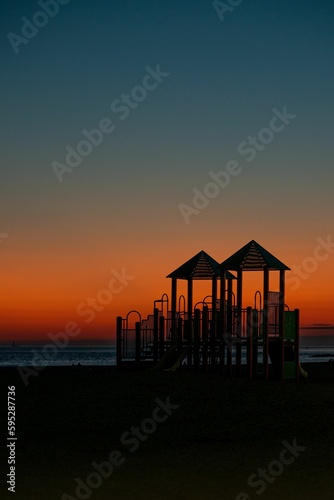 Beautiful shot of a bright orange blue sunset sky over playground silhouettes on Brighton Beach © Apshinashvili/Wirestock Creators