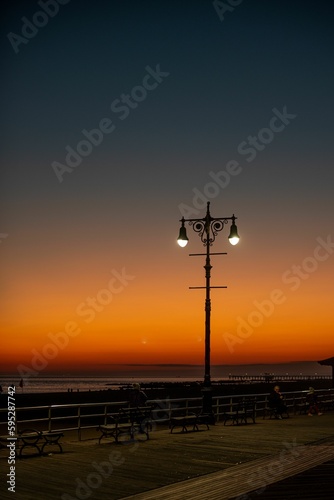 Beautiful shot of a bright orange blue sunset sky over lamp post silhouettes on Brighton Beach