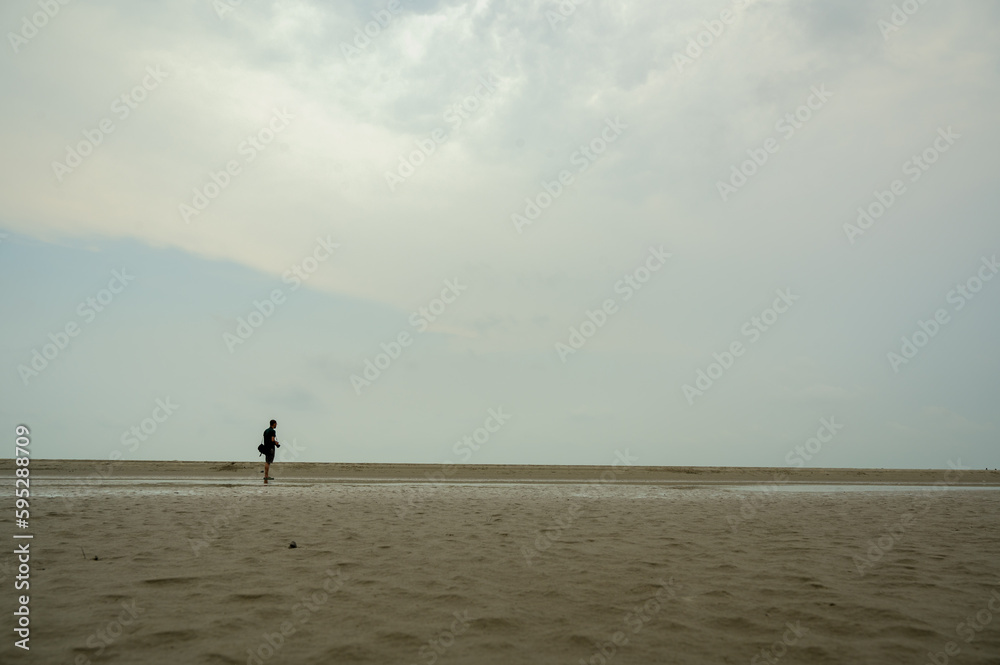 landscape of Bakkhali sea shore. Silhouette of a man running on the beach at sunset.
