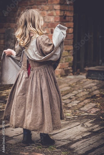 Little girl wearing an old-fashioned brown dress.