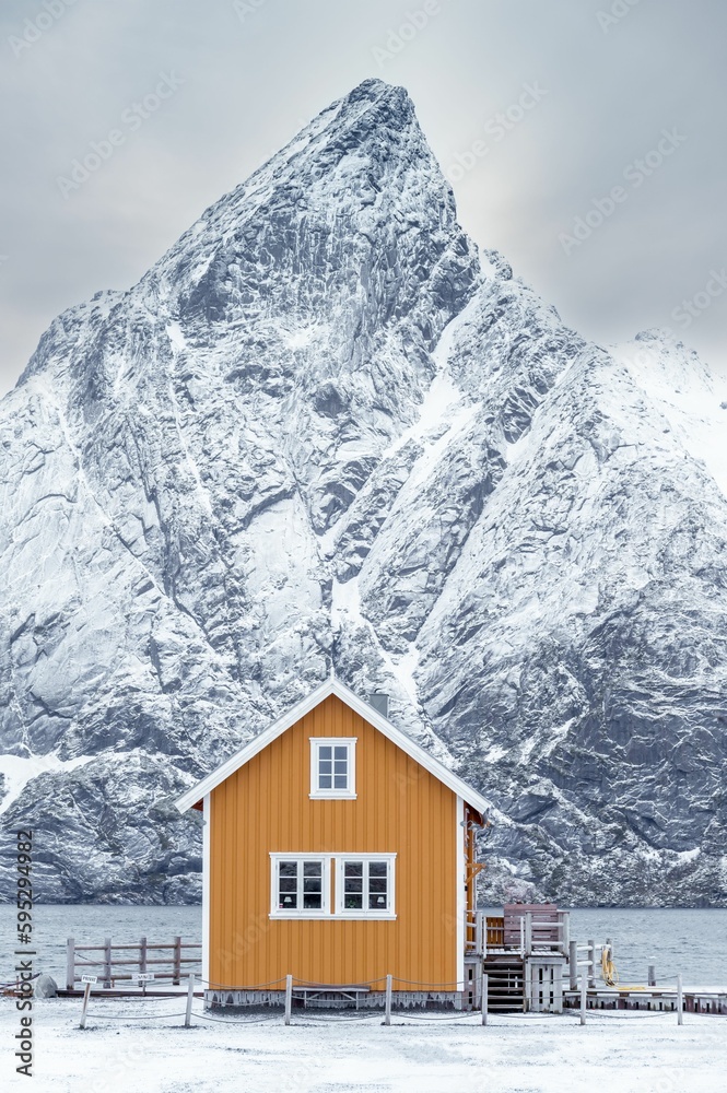 House by the sea with snowy mountains in the background in Lofoten Islands, Norway