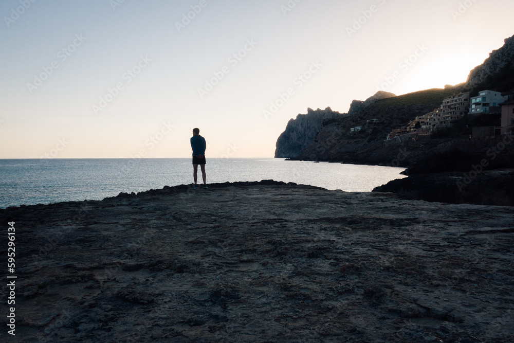 un homme se promène sur le littoral. Balade pensive à Majorque. Silhouette d'un homme au bord de la mer méditerranée. Admirer le paysage aux Baléares. Matin sur le littoral maritime. 