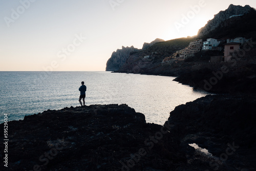un homme se promène sur le littoral. Balade pensive à Majorque. Silhouette d'un homme au bord de la mer méditerranée. Admirer le paysage aux Baléares. Matin sur le littoral maritime. 