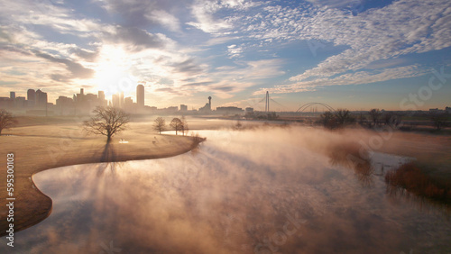 Mist on a cool fall morning on lake at sunrise with modern Dallas skyline and bridge in the background. 