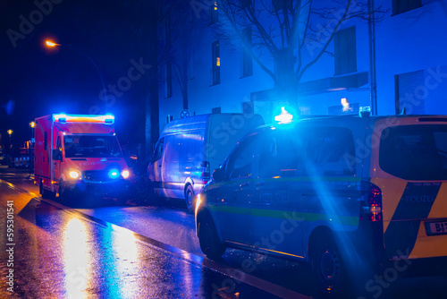 German Ambulance and Police Car at rainy night, blue light, medical transport, Berlin, Germany
