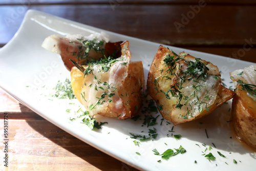 Potato baked in bacon on white plate