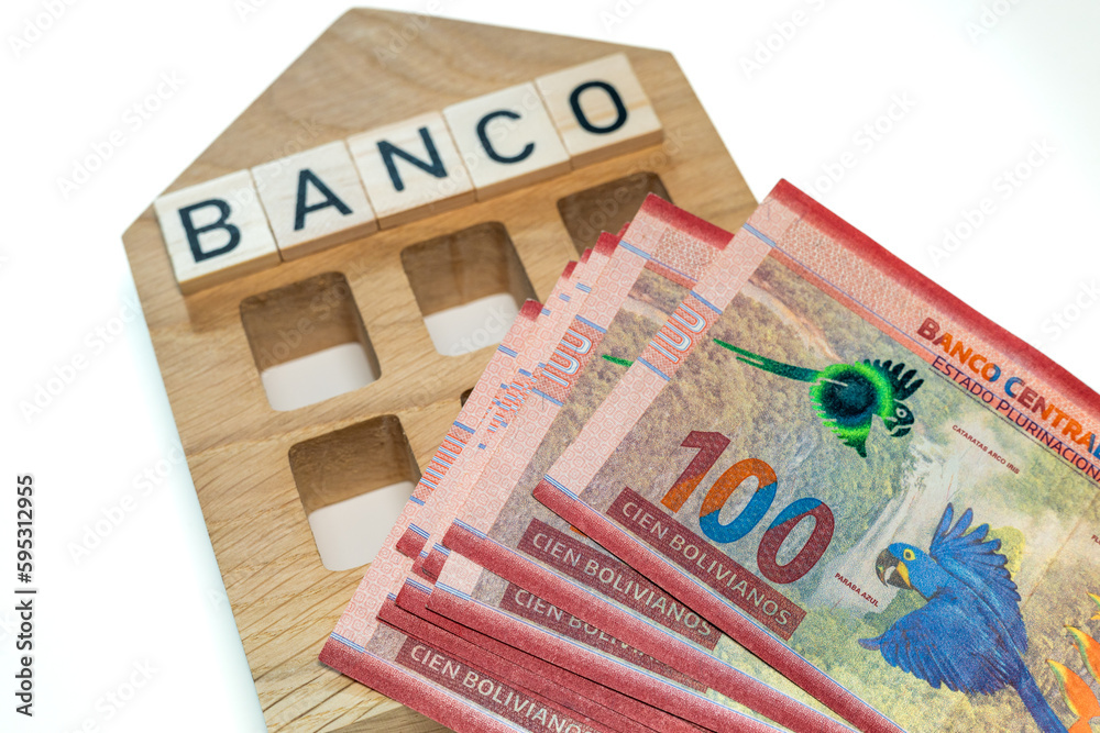 Bolivian money and the symbol of the bank of Colombia, a wooden miniature with the inscription banco, A lot of highest denomination banknotes, financial and business concept - obrazy, fototapety, plakaty 