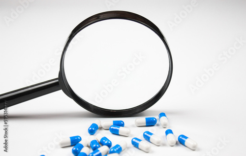 Magnifier and capsules medical. Study of drugs, study of pills concept. Medicines and a magnifying glass.