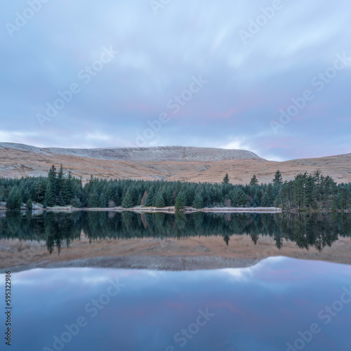 Mountains and treeline, reflected in the calm waters of a mountain lake. Brecon Beacons