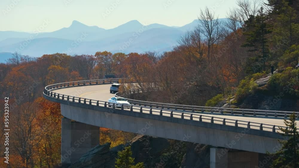Mountain fall landscape with Linn Cove Viaduct, near Blowing Rock, Blue Ridge Parkway, North Carolina, USA. Driving cars on scenic road between autumnal woods Mountain fall landscape with Linn Cove Viaduct, near Blowing Rock, Blue Ridge Parkway, North Carolina, USA. Driving cars on scenic road between autumnal woods