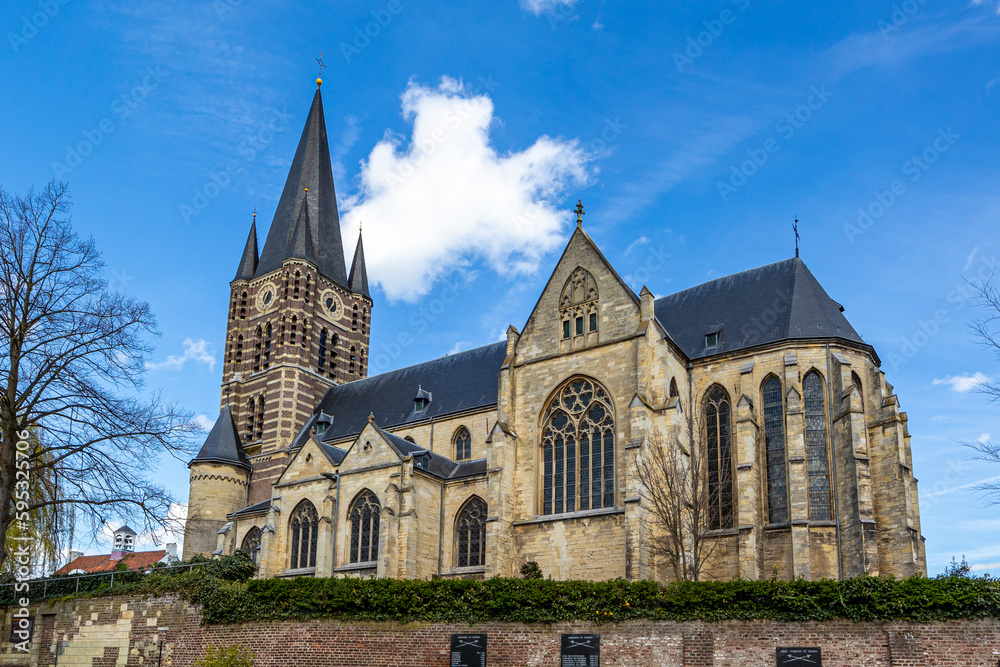 Impressive roman catholic church of St. Michael Abbey seen from south against blue sky, bell tower with its clock and huge windows, sunny day in Thorn, Midden-Limburg in the Netherlands