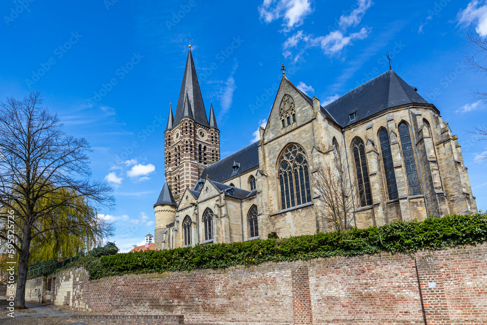 Low angle perspective of Roman Catholic St. Michael Abbey church seen from the south against blue sky, bell tower with its clock and huge windows, sunny day in Thorn, Midden-Limburg in the Netherlands