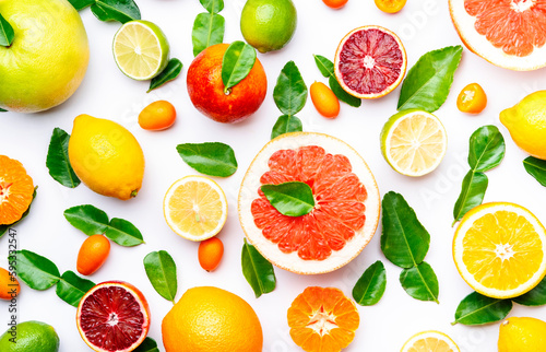 Citrus fruit food background  top view. Mix of different whole and sliced fruits  orange  grapefruit  lime and other with leaves on  white table