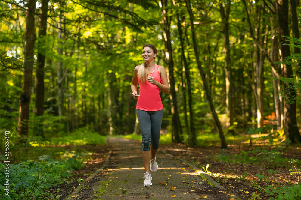 Beautiful young woman in pink top jogging in park. Healthy girl lifestyle background with copy space Beautiful young woman in pink top jogging in park. Healthy girl lifestyle background with copy space