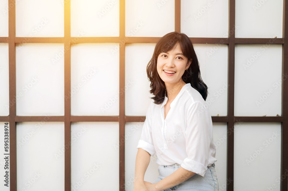 Portrait beautiful young asian woman happiness sitting on wooden grid wall, Happy female is smiling on wooden grid wall, wellness people concept.