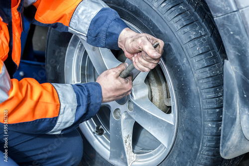 Car wheel replacement. Self-service tire fitting concept. Using a wheel wrench to twist the wheel nuts.
