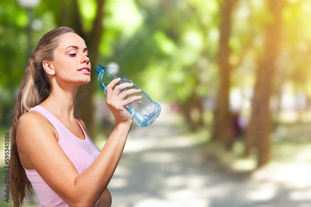 Happy slim young woman drinking clean water after workout Happy slim young woman drinking clean water after workout