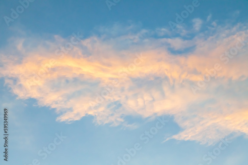 clouds on a blue sky backlit in yellow and orange at early sunset. concept of fresh air and cleanliness