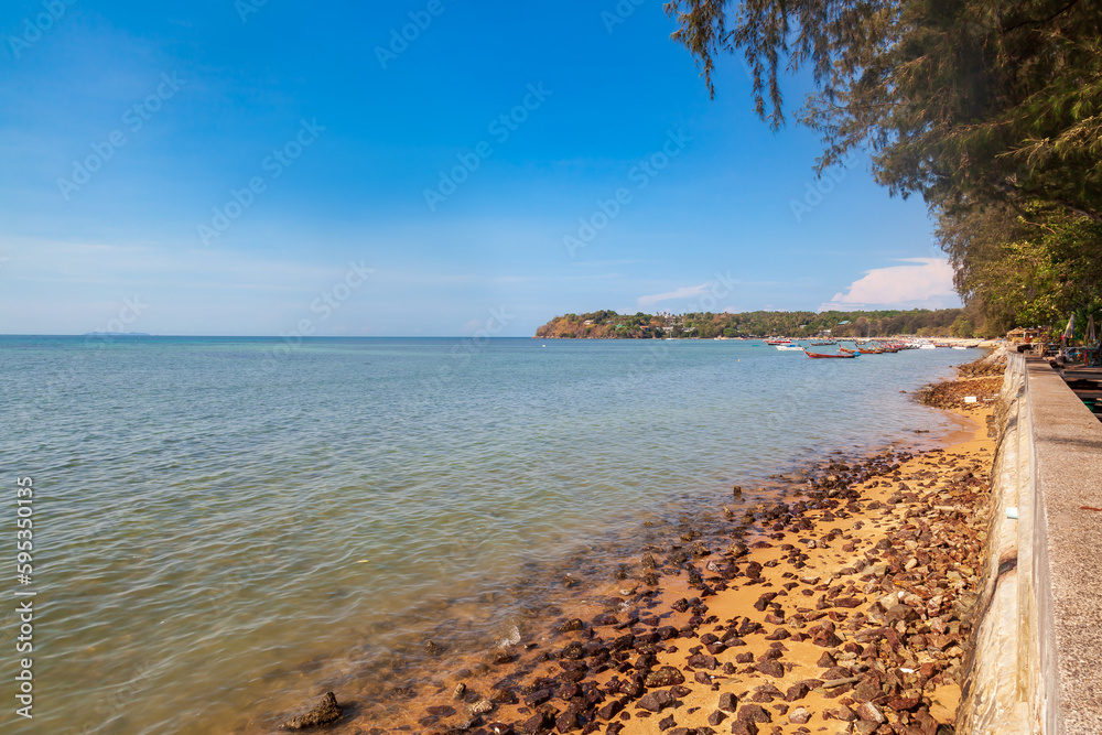 Sea view from rawai beach promenade with rocks and clear water under blue sky