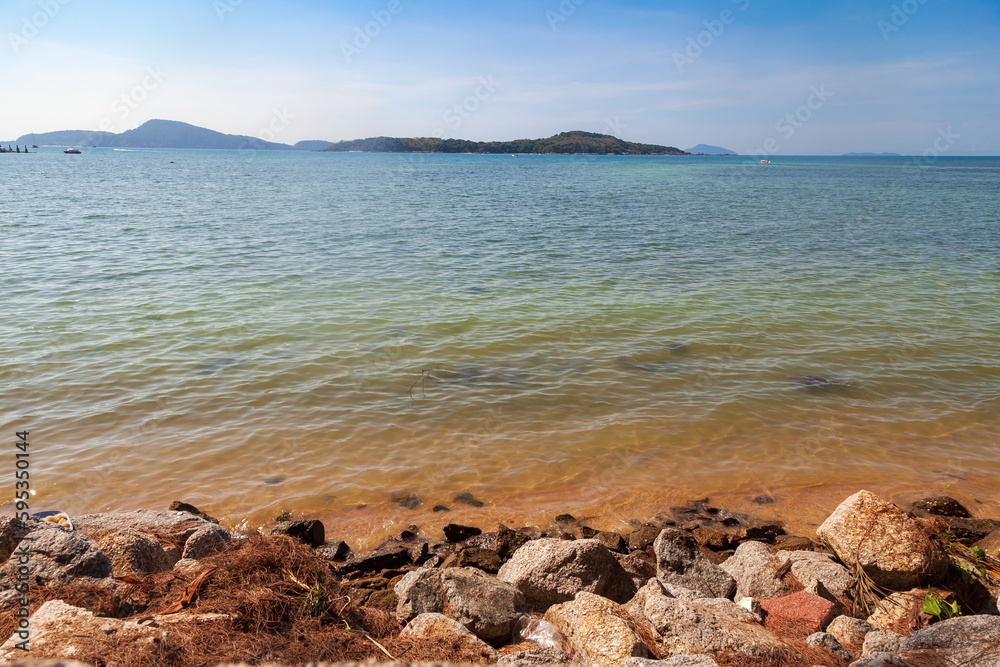 Sea view from rawai beach promenade with rocks and clear water under blue sky Sea view from rawai beach promenade with rocks and clear water under blue sky