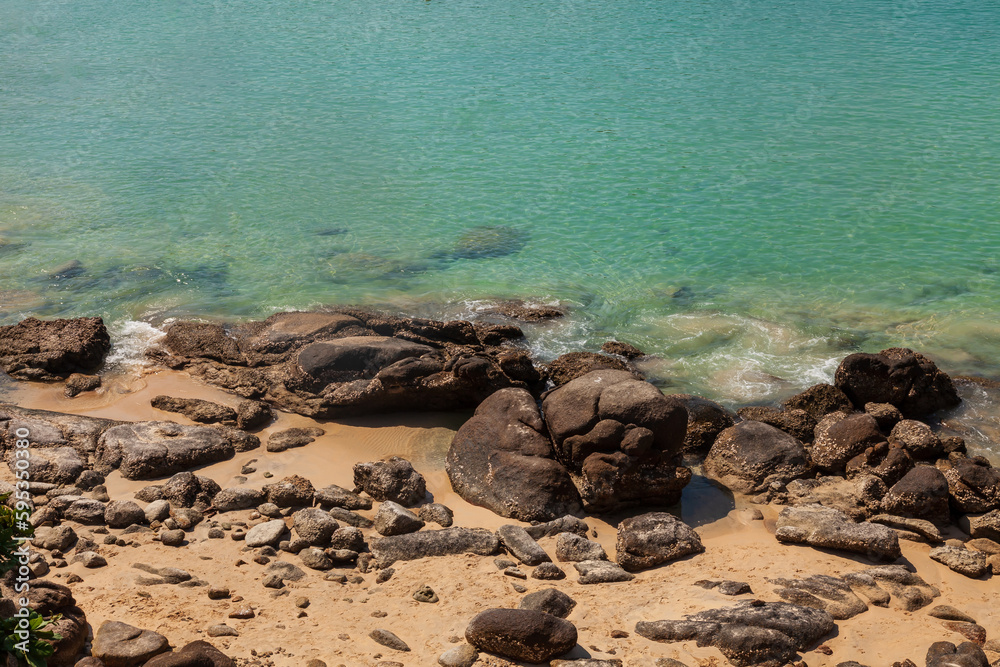 Obraz premium Seashore with sand stones and turquoise clear water on the beach. Tourist travel to thailand on nai harn beach