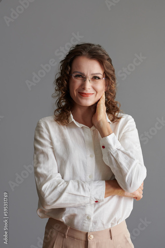 Portrait of smiling mature woman in glasses touching face and looking at camea
