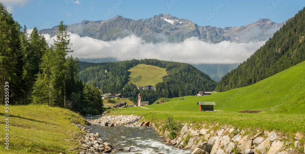 Summer view on the charming Austrian village Umhausen with the rive ötz in the foreground and surrounding mountains in the background. Tirol, Austria. summer, vacations, idyllic.