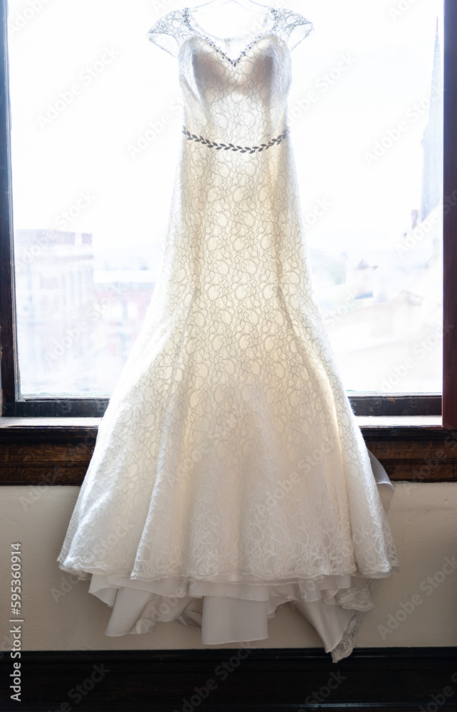 Wedding Dress Hanging in Front of a Window Wedding Dress Hanging in Front of a Window